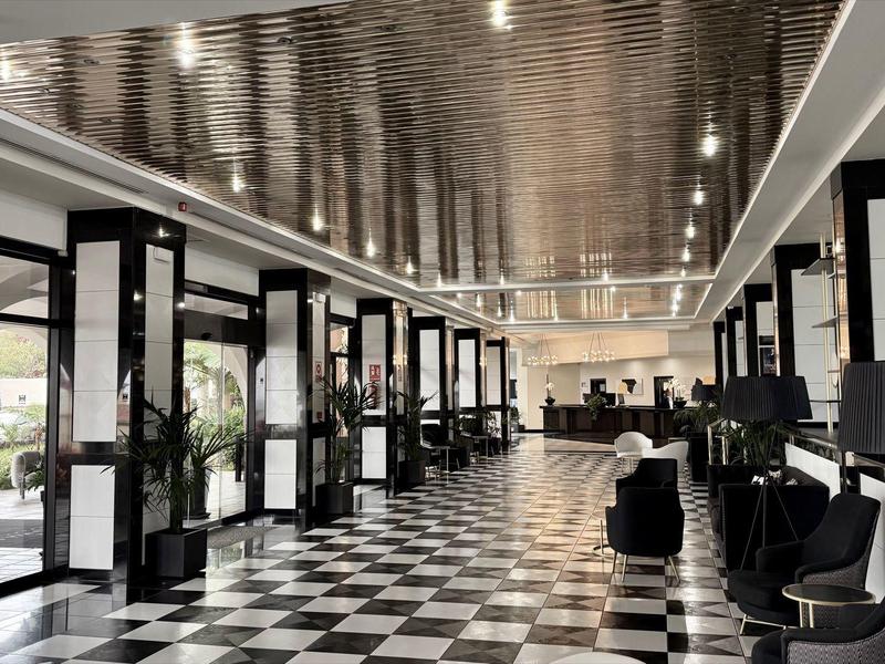 Grande hall dell'hotel con pavimento a scacchiera bianco e nero e arredamento moderno.