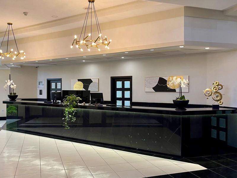 Reception moderna dell'hotel con lungo bancone nero e lampadari eleganti.