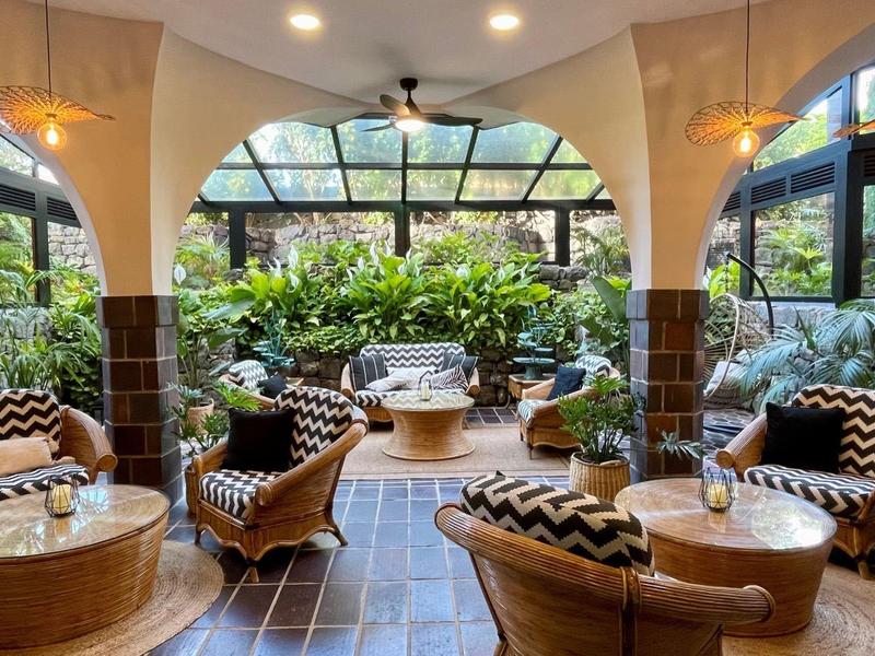 Lounge dell'hotel luminosa con arredamento moderno, poltrone rotonde e grandi finestre con vista sul verde.