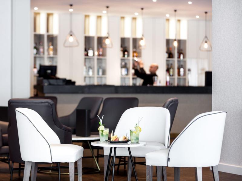 Elegantní lounge prostor s bílými a černými křesly a malými stolky.