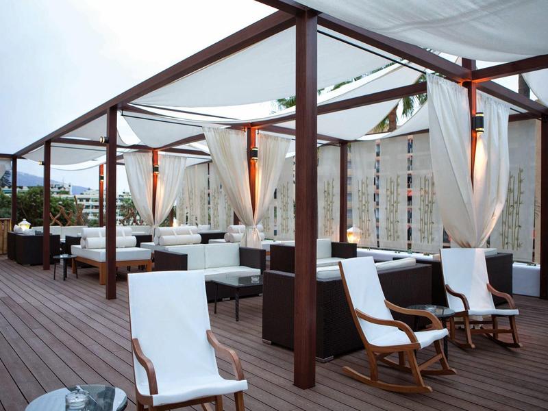 Elegante terraza en la azotea con sillones blancos y suelo de madera en ambiente relajado de hotel.