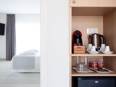 Moderne hotelkamer met koffiemachine, waterkoker en servies op open plank.