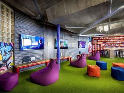 Moderne lounge met kleurrijke zitzakken en groene vloerbedekking in een hotel.