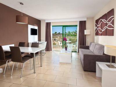 Lichte woonkamer met eettafel, bank en balkon met uitzicht op groen landschap.