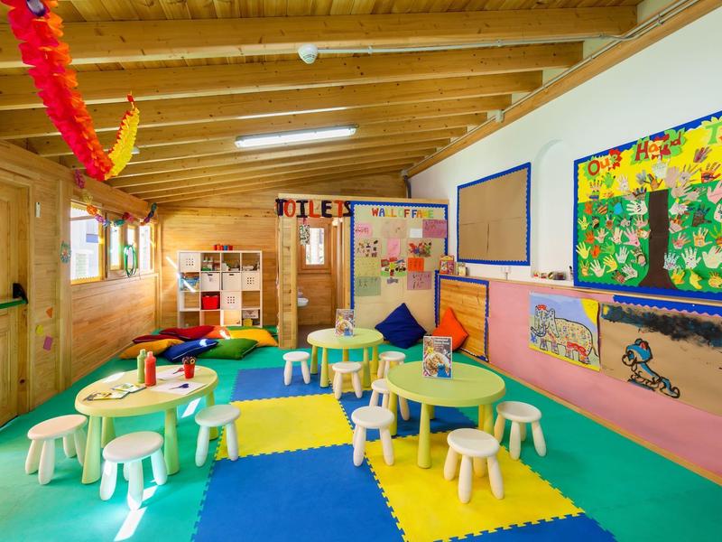 Kleurrijke kinderruimte met tafels, stoelen en wanddecoraties in een hotel