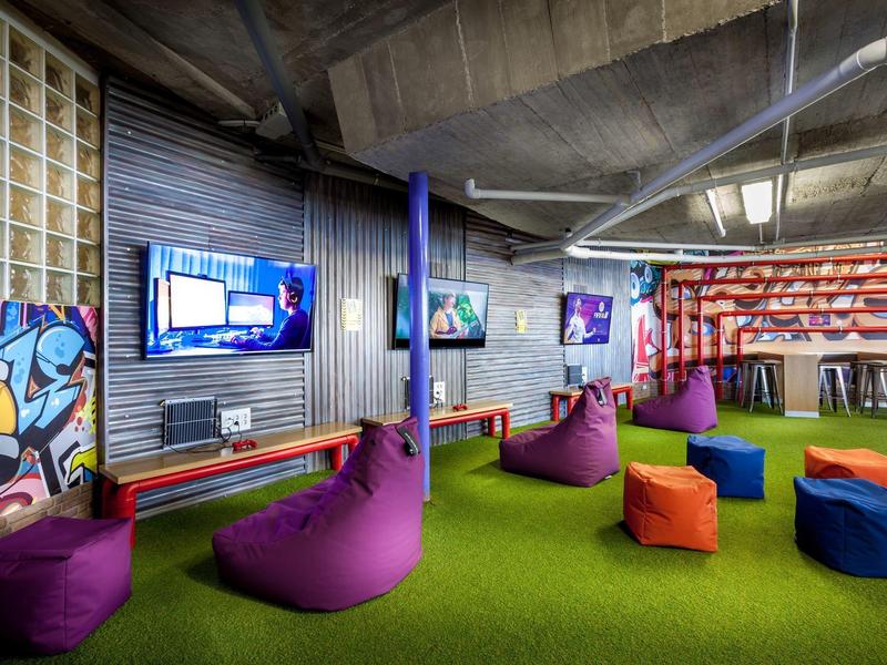 Moderne lounge met kleurrijke zitzakken en groene vloerbedekking in een hotel.