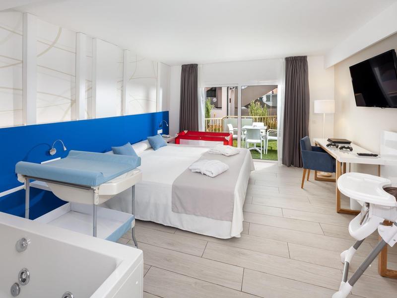 Moderne hotelkamer met tweepersoonsbed, commode, balkon en televisie aan de muur.