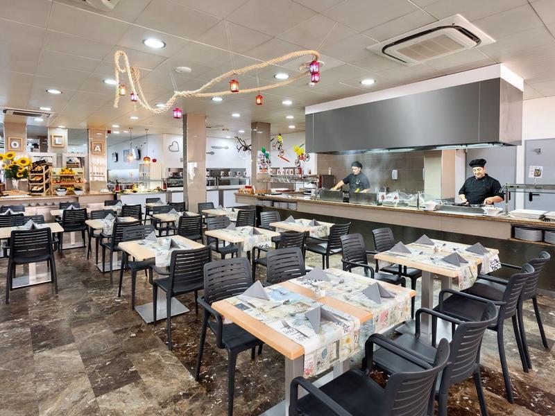 Ruime, moderne eetzaal met gedekte tafels en een open keuken.