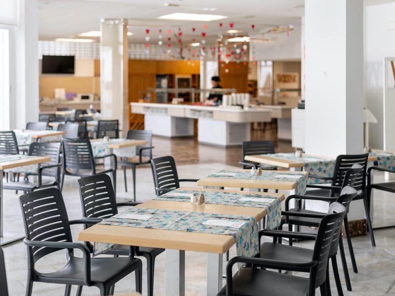 Moderne eetruimte met houten tafels en zwarte kunststofstoelen in een hotel.