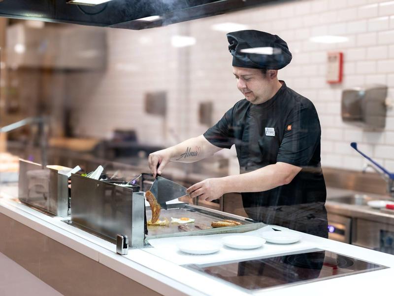 Kok in zwarte kleding bereidt eten in een moderne keukenstation