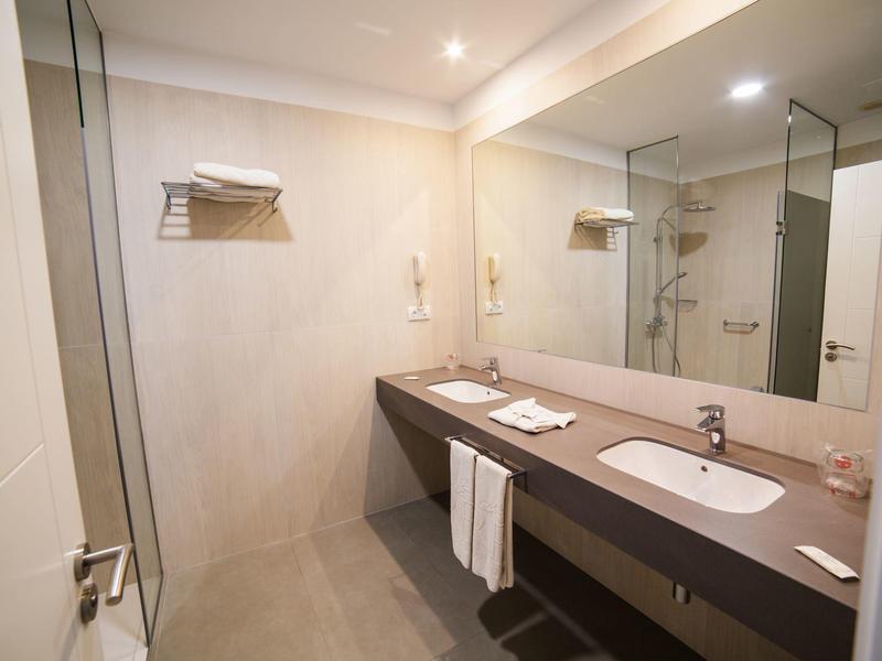 Modern bathroom with large mirror wall, double sinks, and towels.