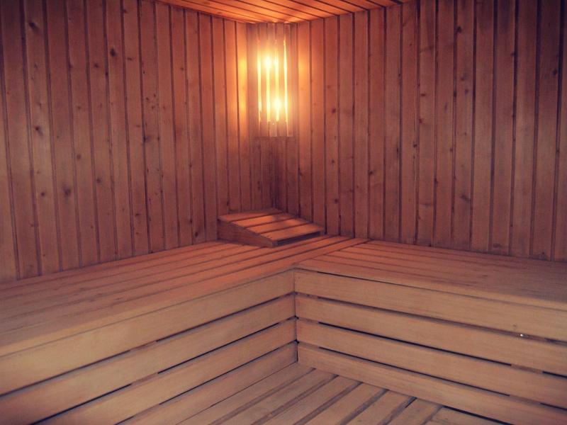 Interior of a wooden sauna with benches and warm light on the wall.