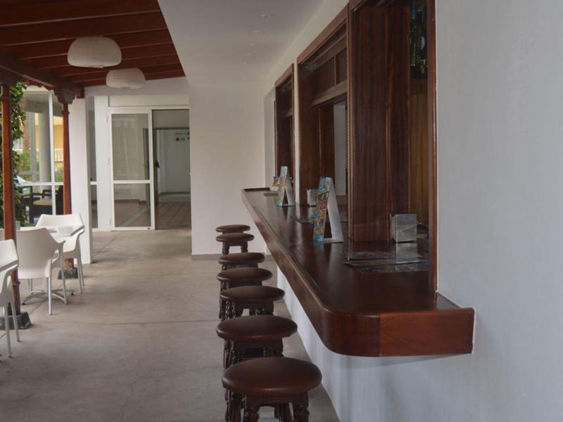 Modern balcony with bar stools and white chairs in a hotel setting.