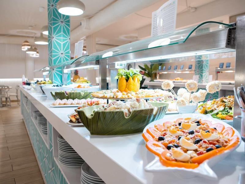 Buffet avec légumes frais, salades et entrées dans un restaurant lumineux.