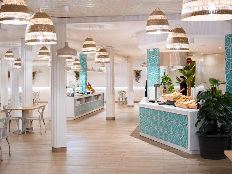 Café lumineux et moderne avec comptoir bleu décoré et lampes suspendues.