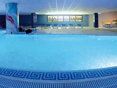 Beleuchteter Außenpool bei Nacht in modernem Hotel mit breitem Bereich und Liegestühlen