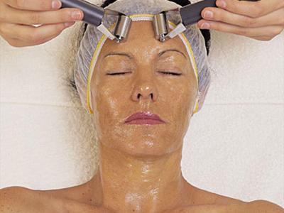 Frau erhält Gesichtsmassage mit Elektrogeräten in einem Spa.