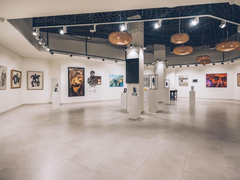 Grote, lichte tentoonstellingsruimte met moderne kunst aan de muren in een hotel.