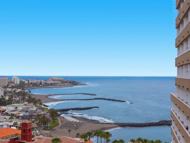 Vista al mar con línea costera y edificios en la playa bajo cielo despejado.