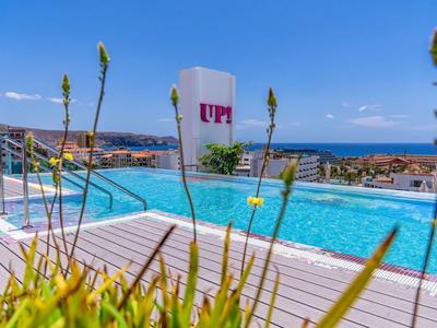 Moderní bazén s výhledem na moře a sluneční terasou za slunečného dne.