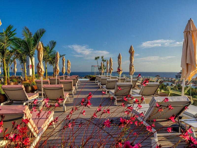 Lehátka s uzavřenými slunečníky s výhledem na moře za slunečného dne.