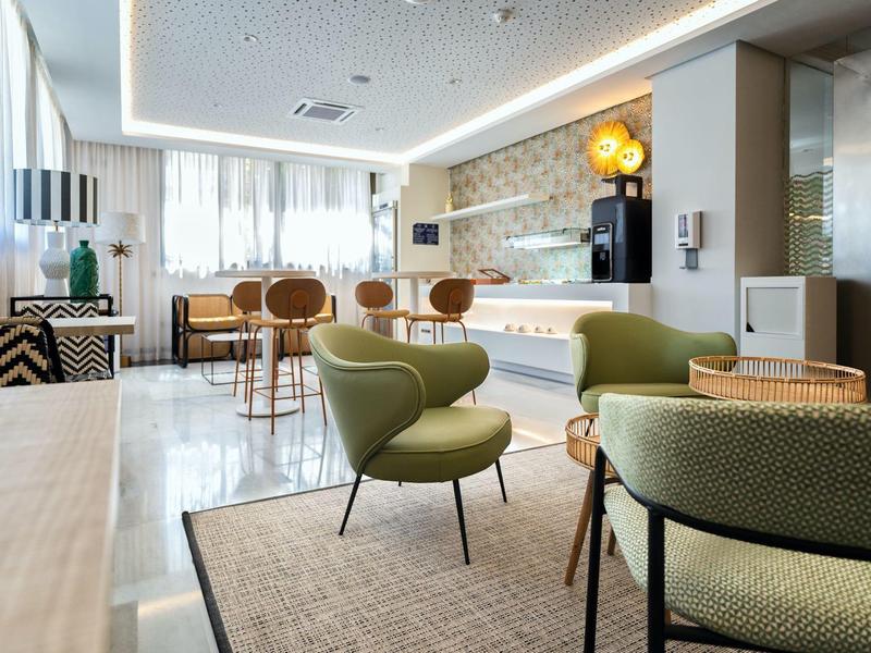 Moderní hotelová lounge s pohodlnými křesly, dřevěnými židlemi a dekorativními lampami.