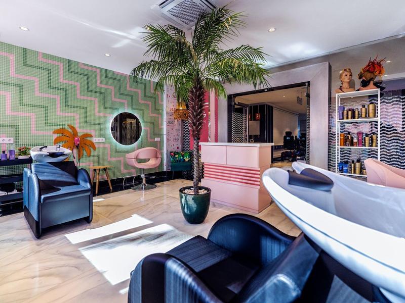 Moderní kadeřnictví s koženými křesly a velkou pokojovou rostlinou v světlém prostředí