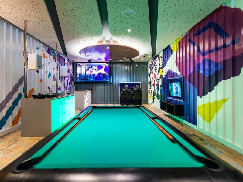 Moderní kulečníkový stůl v barevně a umělecky navržené místnosti s televizory.