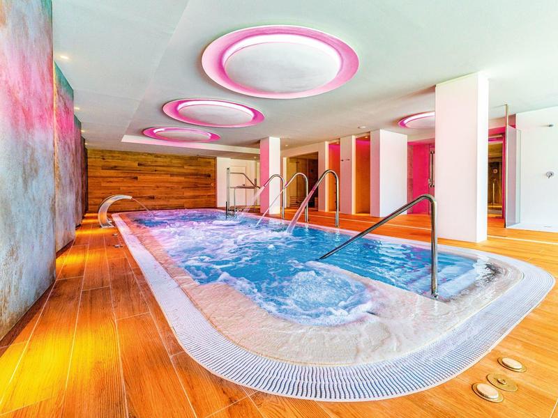 Moderní wellness s vířivkou a teplou dřevěnou podlahou v hotelu.