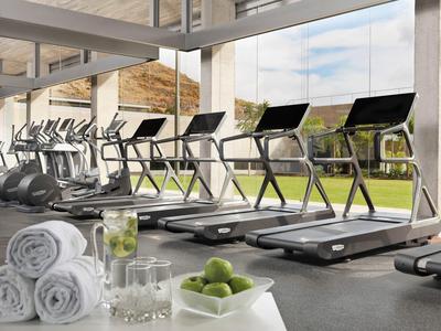 Moderne Fitnessraum mit Laufbändern, großen Fenstern und frischen Handtüchern, Limetten im Glas.