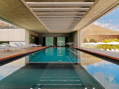 Moderner Innenpool mit langen Schwimmbahnen, Liegestühlen und großem Glasfenster zum Außenbereich.