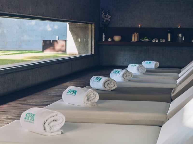 Área de descanso con tumbonas y toallas dobladas junto a una ventana con vista exterior.