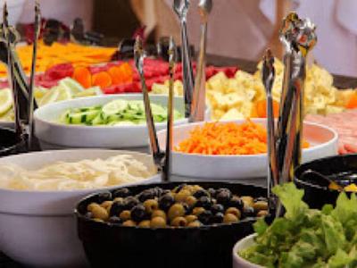 Varias fuentes con ensaladas y verduras frescas dispuestas en un buffet.