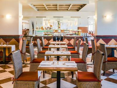 Salle à manger d'hôtel lumineuse avec des tables bien disposées et des chaises confortables aux tons chauds.