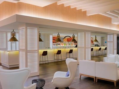 Elegante Hotelbar mit modernen weißen Möbeln und beleuchtetem Tresen.