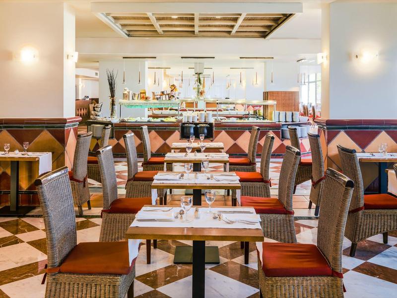 Salle à manger d'hôtel lumineuse avec des tables bien disposées et des chaises confortables aux tons chauds.