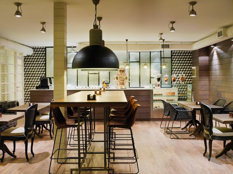 Espace repas moderne avec tabourets hauts, suspensions et murs carrelés à motif.