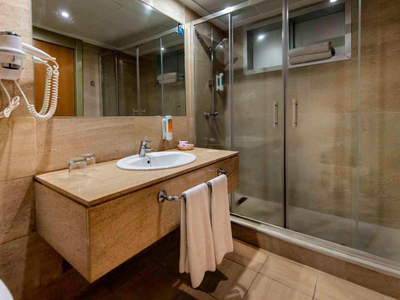 Modernes Badezimmer mit Holzoptik, Glasdusche, weißem Waschbecken und integriertem Spiegel.