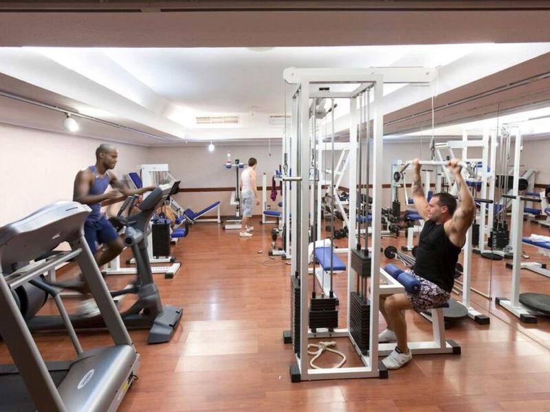 Innenansicht eines Fitnessstudios mit Laufbändern, Kraftgeräten und Personen beim Training.