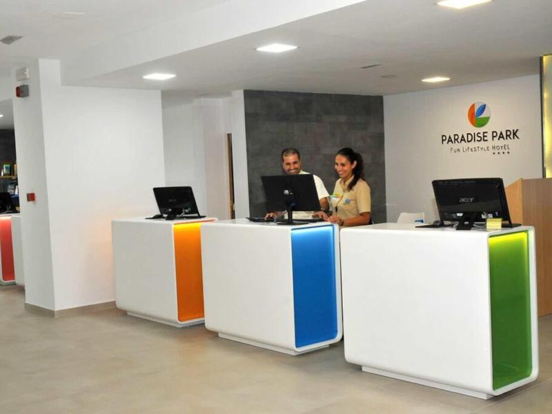 Moderner Empfangsbereich mit bunten Tresen und zwei Personen an der Rezeption in einem Hotel.