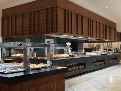 Buffet moderno con pasticceria e personale di cucina in uniforme in uno spazio elegante.