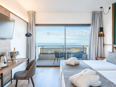 Camera d'hotel moderna con terrazza e vista sul mare.