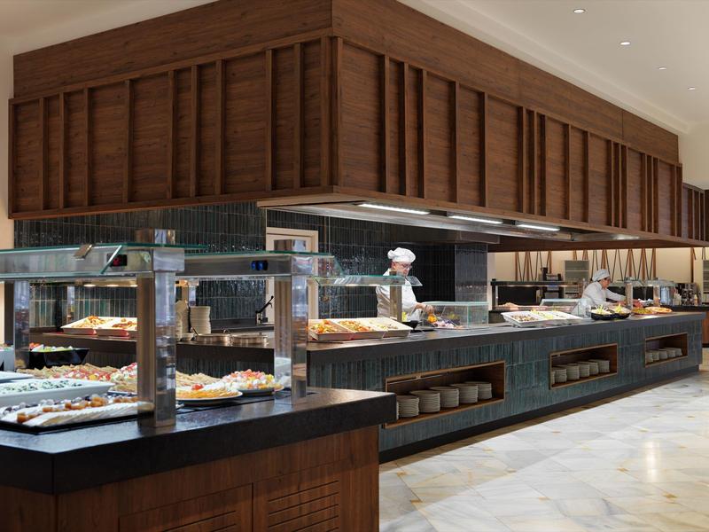 Buffet moderno con pasticceria e personale di cucina in uniforme in uno spazio elegante.