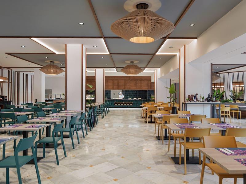 Sala ristorante elegante con tavoli in legno e sedie verdi e beige in un hotel.