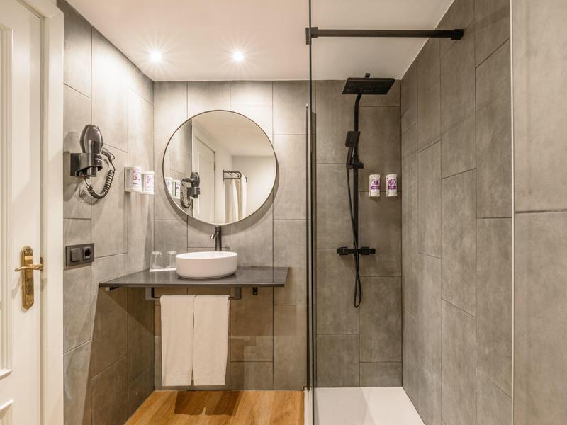 Bagno moderno con doccia a filo pavimento e lavabo su mobile nero.