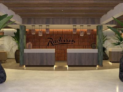 Moderner Hotel-Empfangsbereich mit zwei Rezeptionstheken und grünen Pflanzen.