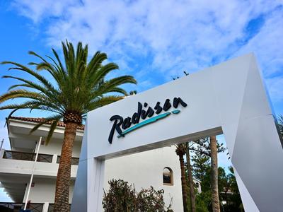 Eingang mit Radisson-Logo und Palmen vor blauem Himmel in einem Hotel