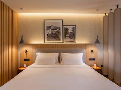 Modernes Hotelzimmer mit großem Bett, Holzpaneelen und zwei Bildern an der Wand.