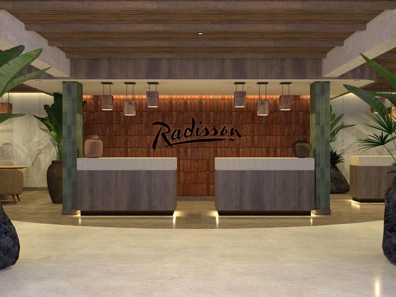 Nowoczesne lobby hotelowe z dwoma recepcjami i zielonymi roślinami.