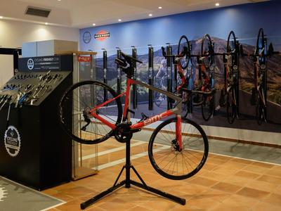Moderní cyklistický obchod s červeným kolem uprostřed a několika koly na zdi.